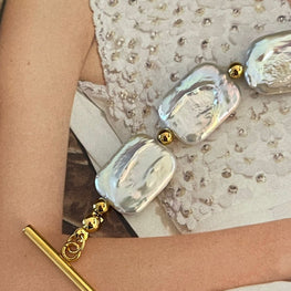 Pulsera Hippie Chic de elegantes Perlas Barrocas blancas naturales con base de acero inoxidable dorado.