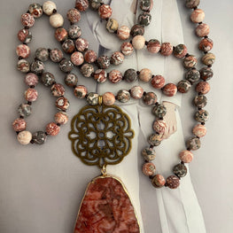 Collar Hippie Chic largo de piedras naturales anudadas en tonos rojos, rosas, blancos y marron, con colgante en los tonos y mandala y precioso mandala envejecido.