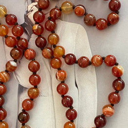 Collar Hippie Chic largo de Agatas anudadas en tonos rojos anaranjados y conector dorado.